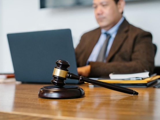 Crop concentrated Asian male judge in formal clothes sitting using modern netbook while working in law office
