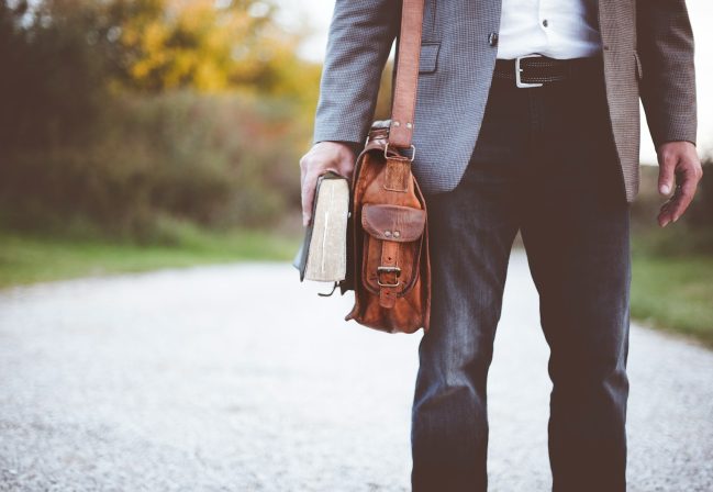 man holding book on road during daytime